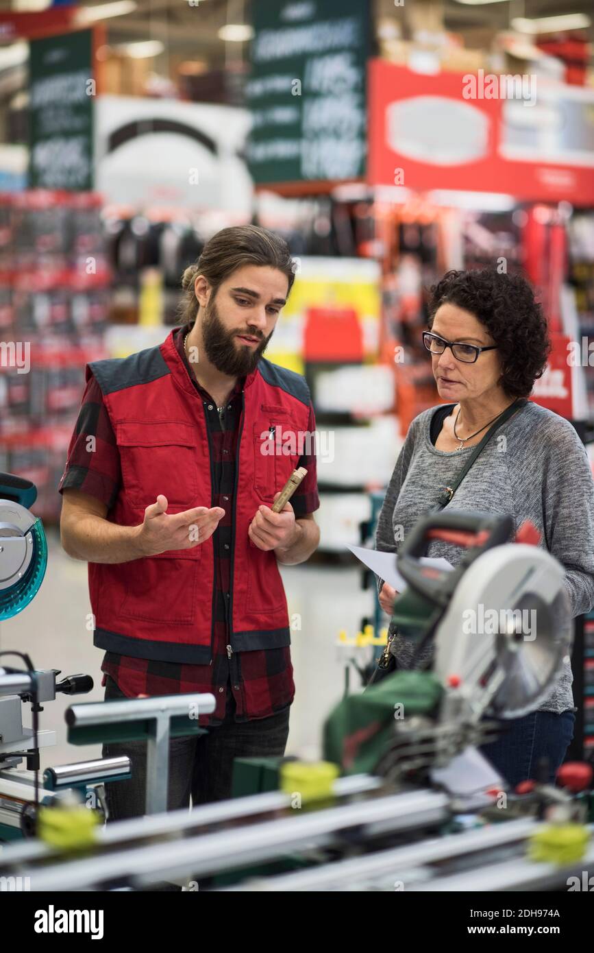 Verkäufer erklärt Elektrowerkzeuge zu reifen Frau im Baumarkt Stockfoto