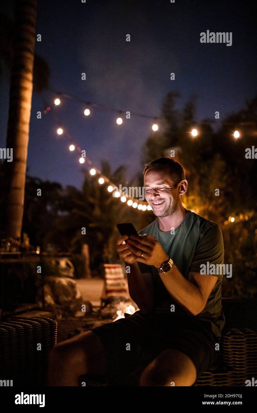 Lächelnder Mann, der während des Sonnenuntergangs im Freien sitzt Stockfoto