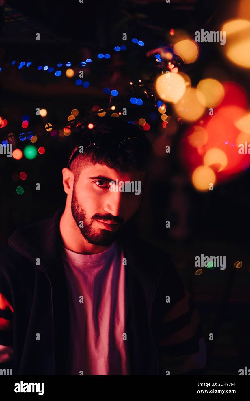 Porträt des selbstbewussten bärtigen Mann gegen beleuchtete bunte Lichter an Bar Stockfoto
