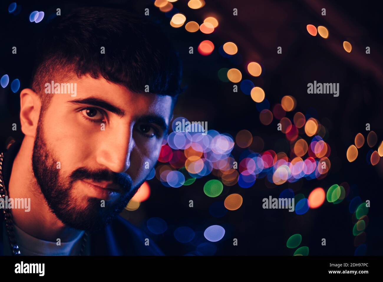 Selbstbewusste junge bärtete im Restaurant gegen bunte Lichter Stockfoto