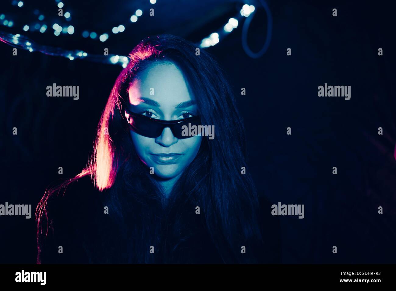 Porträt einer selbstbewussten jungen Frau mit Sonnenbrille im beleuchteten Restaurant Stockfoto