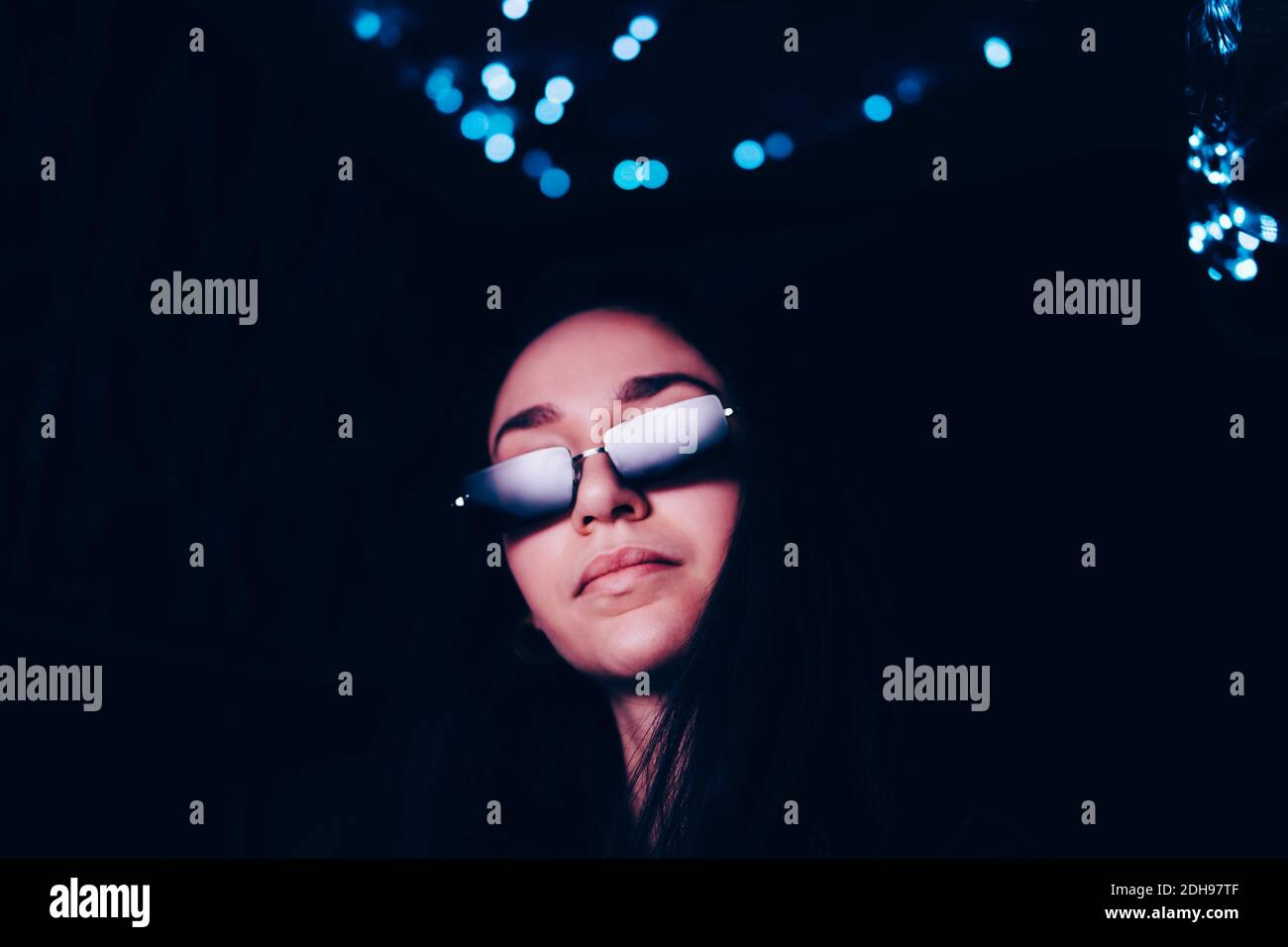 Selbstbewusste junge Frau mit Sonnenbrille im beleuchteten Restaurant Stockfoto
