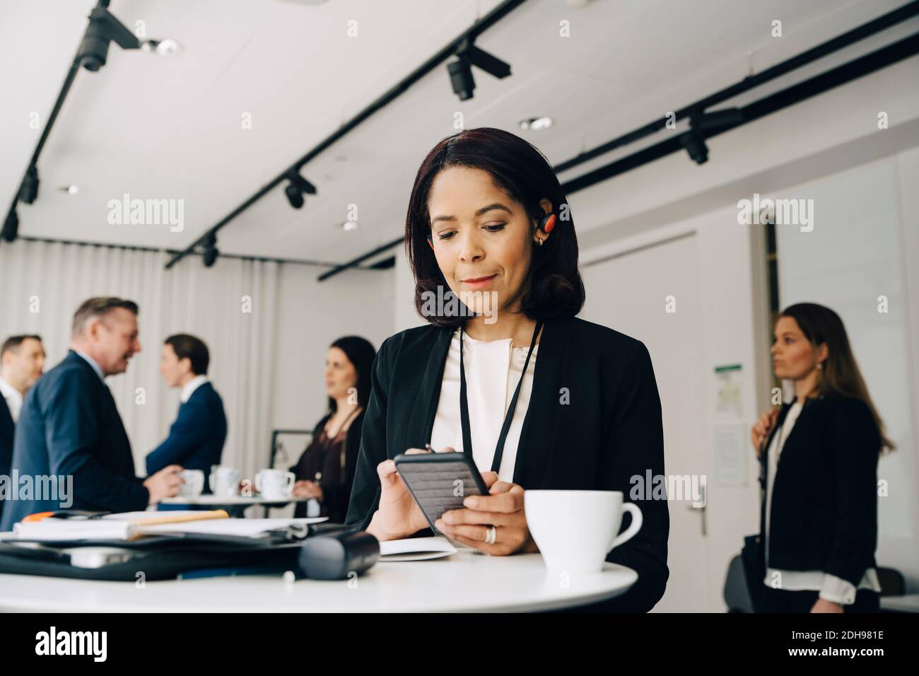 Weibliche Geschäftsperson, die am Tisch steht und das Telefon benutzt Büroarbeitsplatz Stockfoto