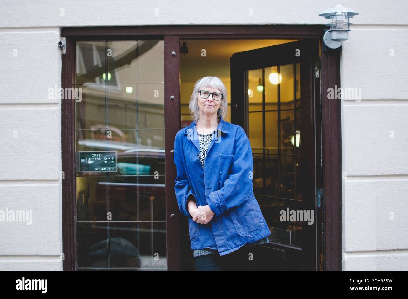 Porträt einer selbstbewussten Besitzerin, die an der Tür des Schmuckstücks steht Speichern Stockfoto