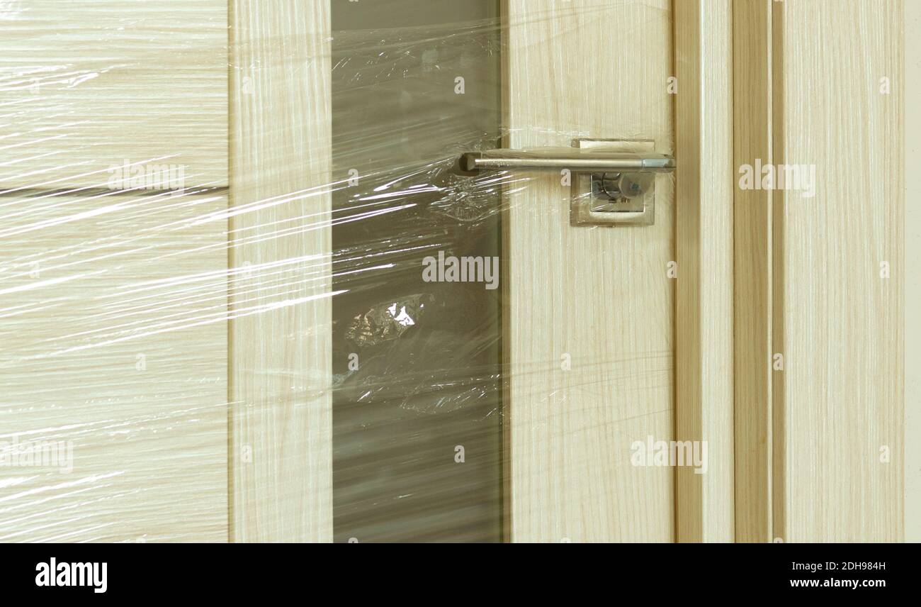 Die neue Tür wird eingebaut und in eine Schutzfolie verpackt  Stockfotografie - Alamy