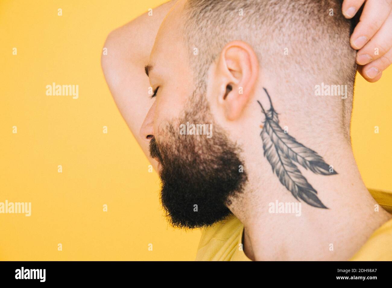 Nahaufnahme von Hals-Tattoo auf Mann vor gelbem Hintergrund Stockfoto
