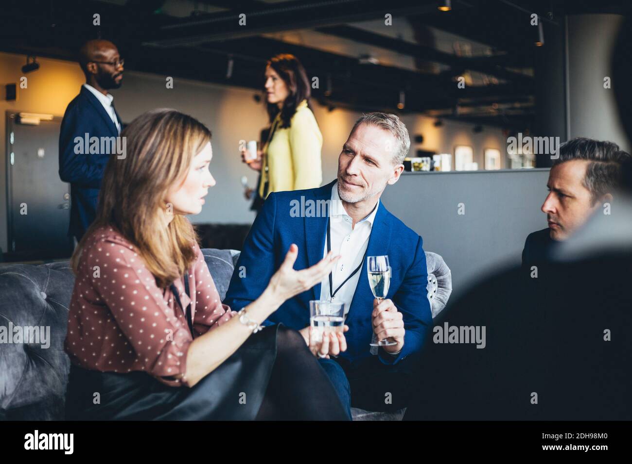 Weibliche professionelle Gespräche mit männlichen Kollegen, während sie im Büro sitzen Stockfoto