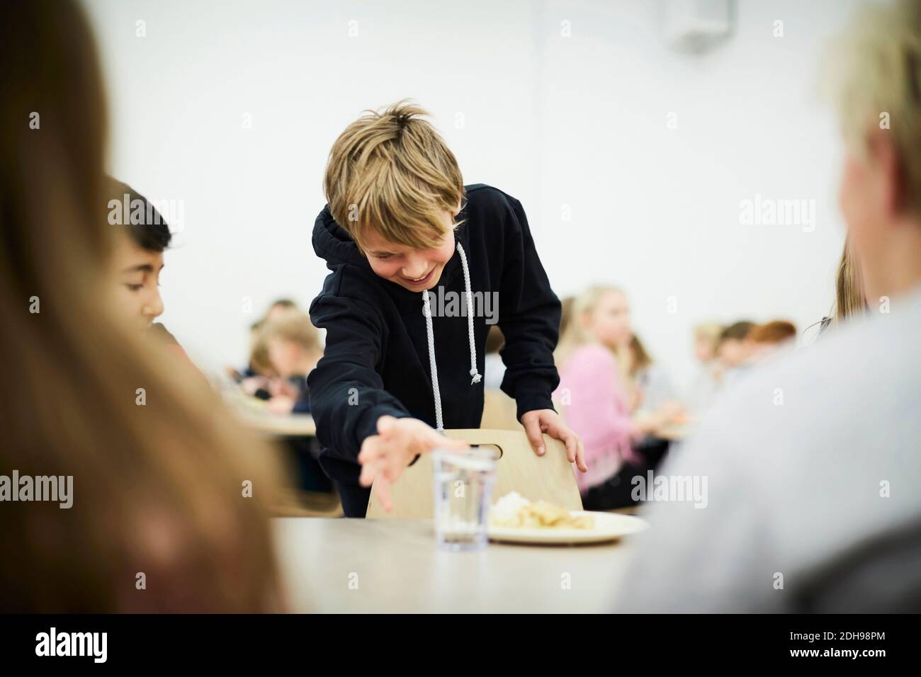 Junge Abholung Glas Trinkwasser in der Schule Cafeteria Stockfoto