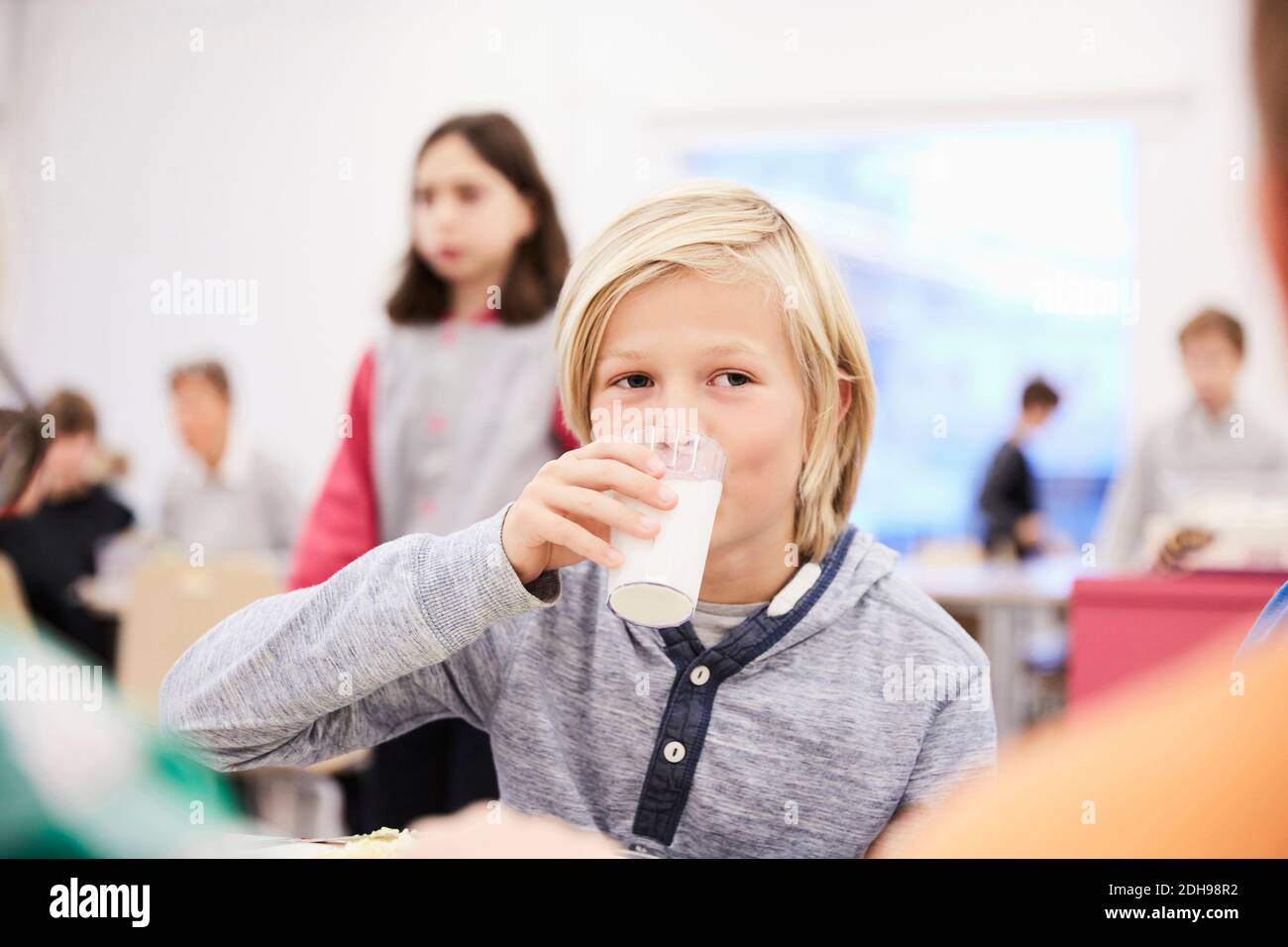 Junge trinkt Milch während der Mittagspause in der Schulkantine Stockfoto