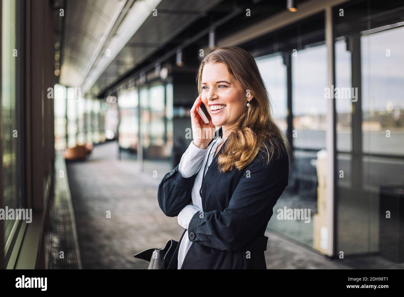 Lächelnde Geschäftsfrau, die am Arbeitsplatz telefoniert Stockfoto