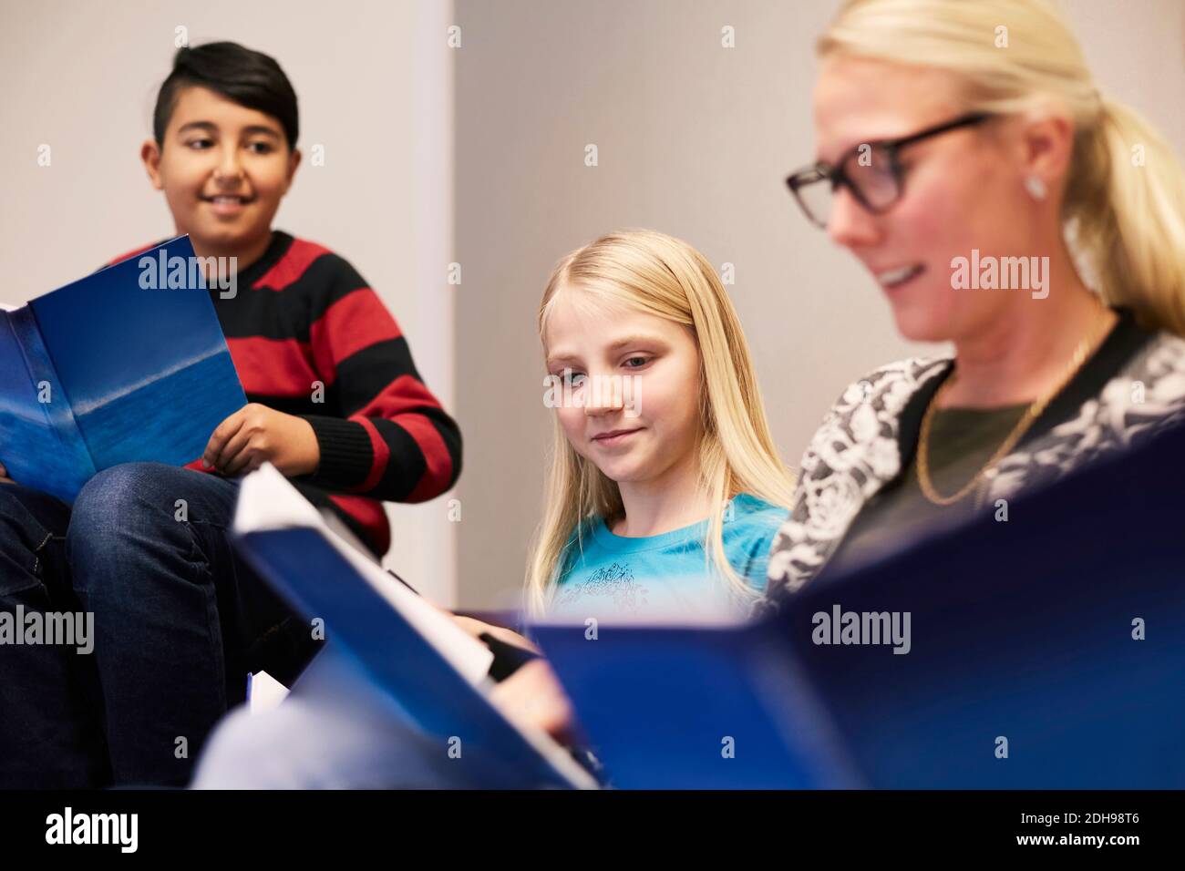 Schüler und Lehrer lesen Bücher im Klassenzimmer Stockfoto
