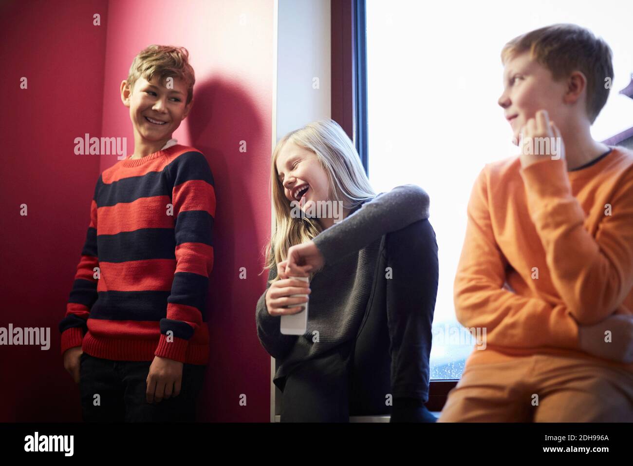 Lächelndes Mädchen Öffnung Flasche mit männlichen Freunden in der Mittelschule Stockfoto