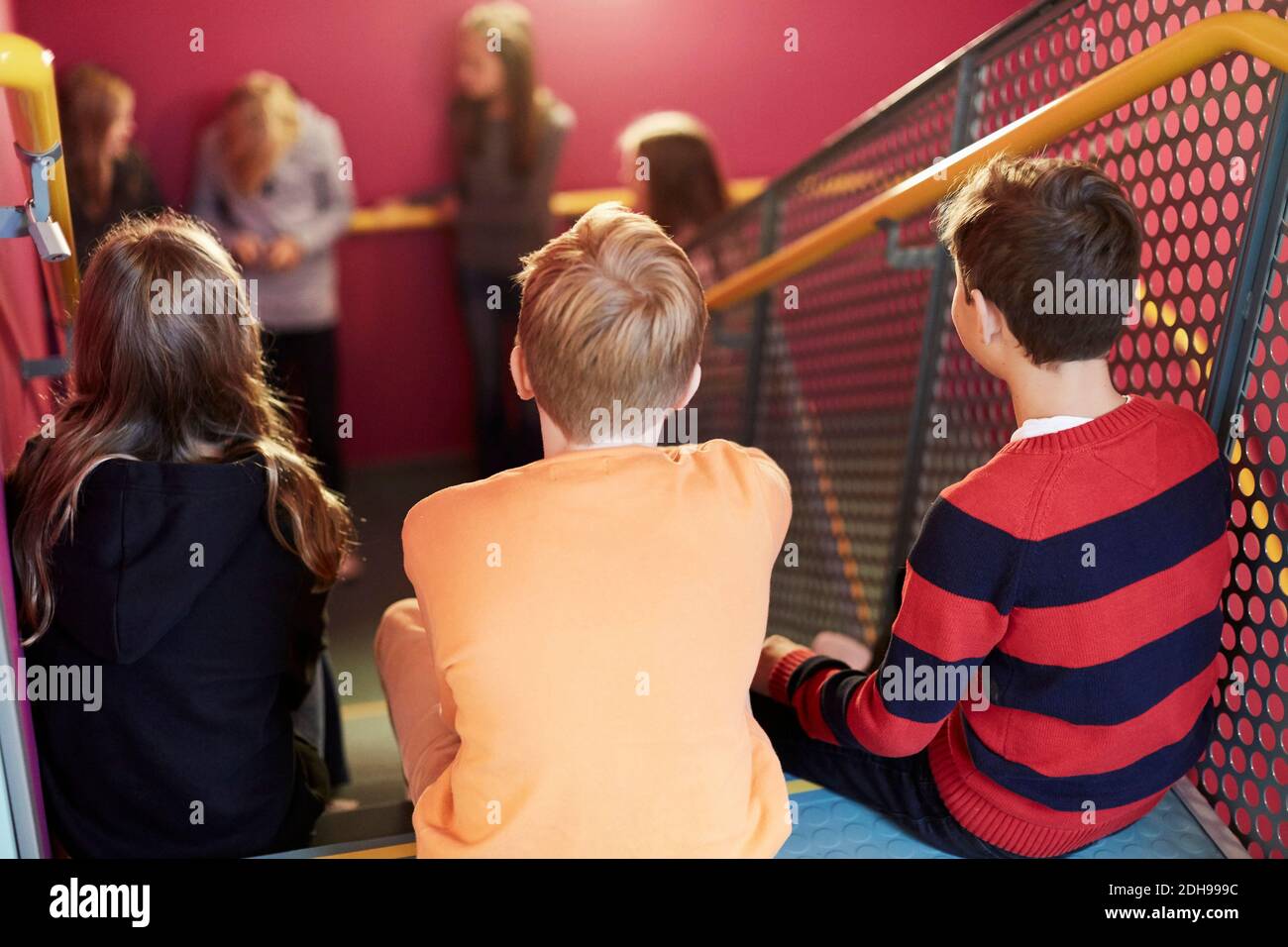 Rückansicht der Junior-High-Studenten auf der Schultreppe sitzen Stockfoto