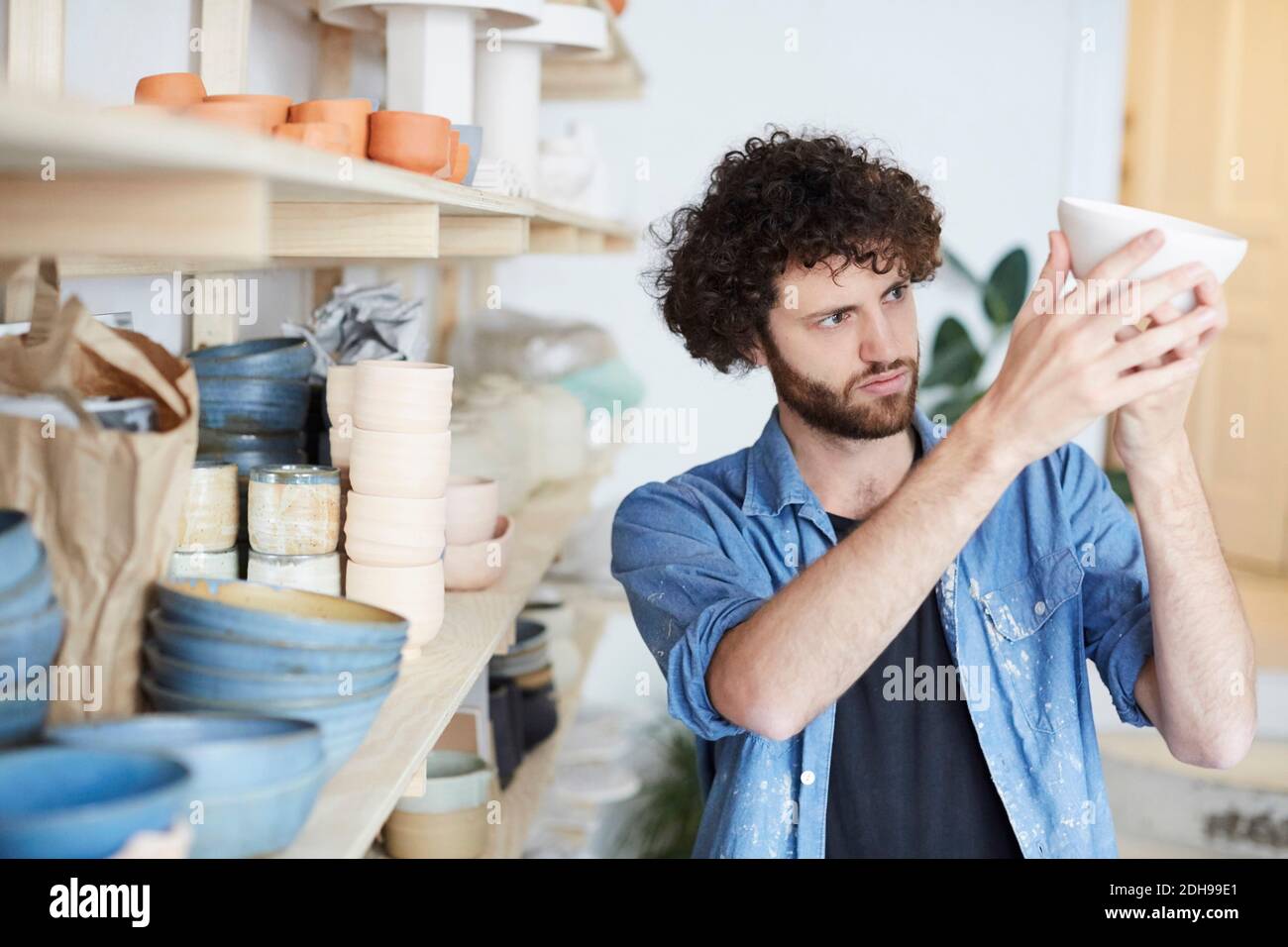 Mittelerwachsener Mann, der die Schale in der Töpferklasse untersucht Stockfoto Mittelerwachsener Mann, der die Schale in der Töpferklasse untersucht Stockfoto