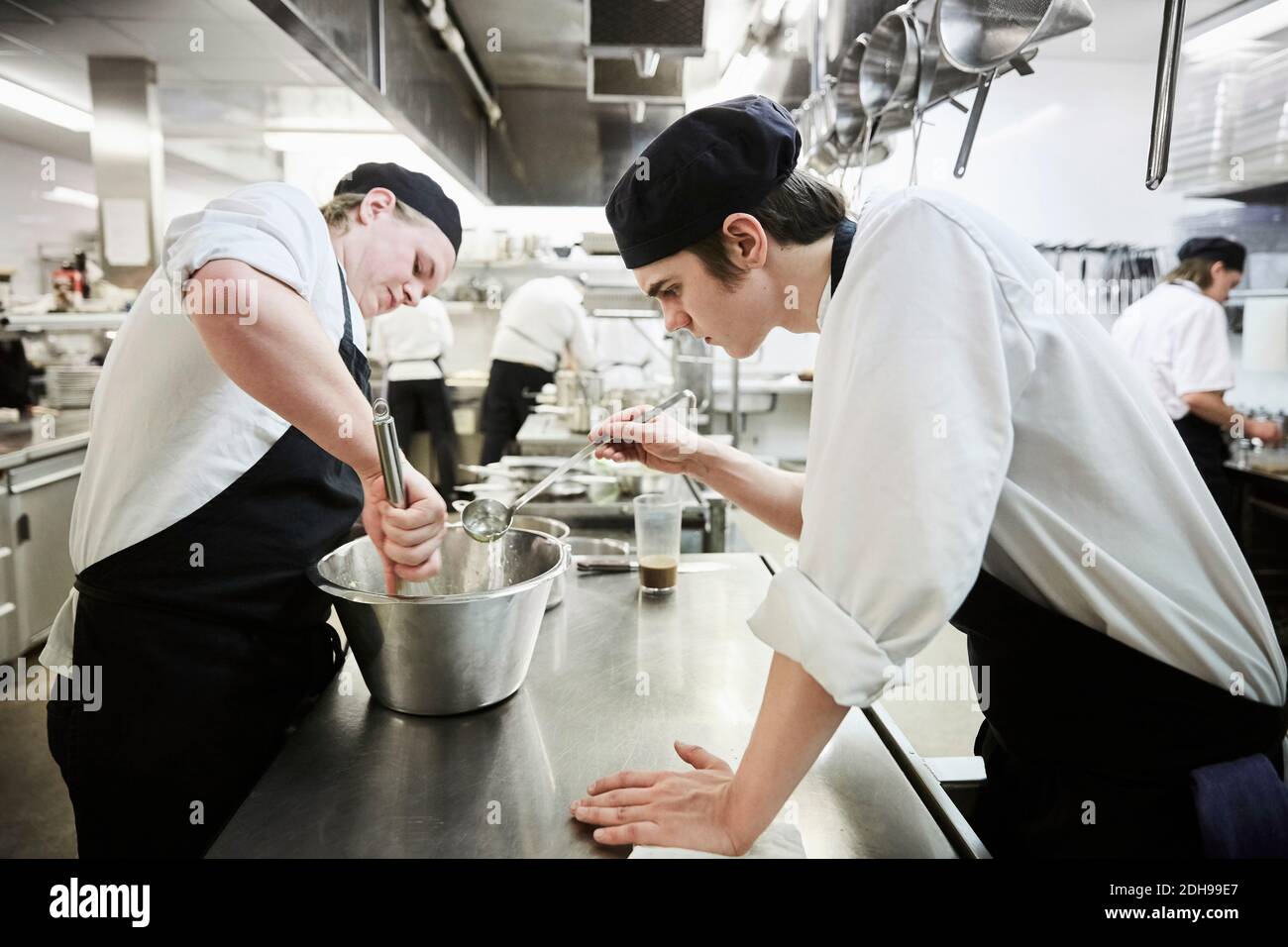 Seitenansicht der männlichen Kochstudenten, die Essen im kommerziellen Bereich zubereiten Küche Stockfoto