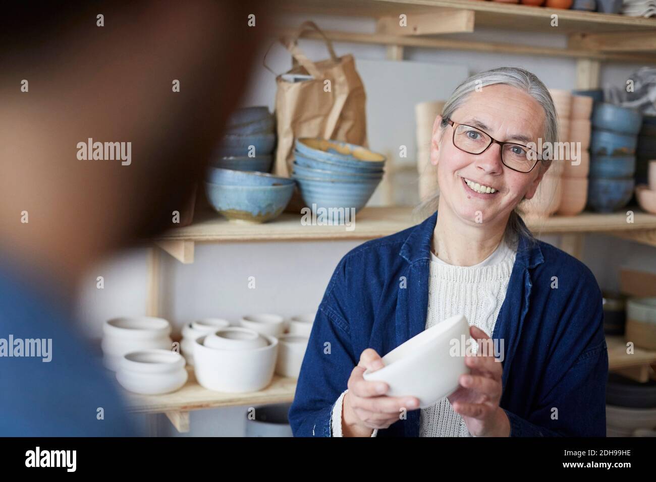 Lächelnde reife Frau diskutieren mit Mann über Schüssel in Keramik Klasse Stockfoto