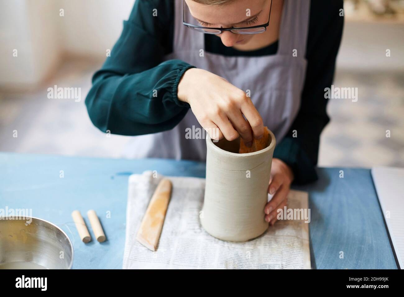 Junge Frau, die Steingut am Tisch im Kunststudio formt Stockfoto