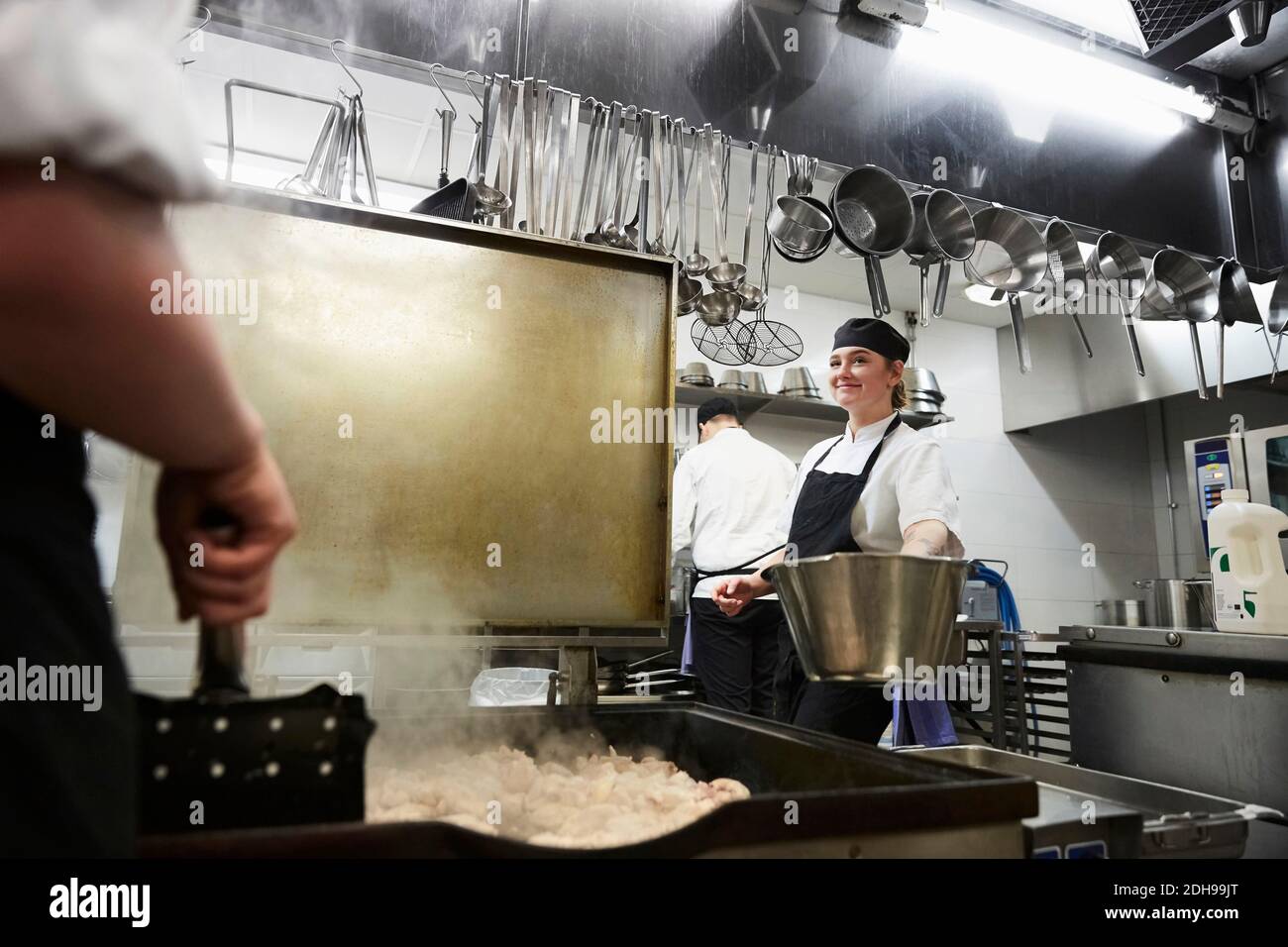 Lächelnde Köchin, die in der kommerziellen Küche arbeitet Stockfoto