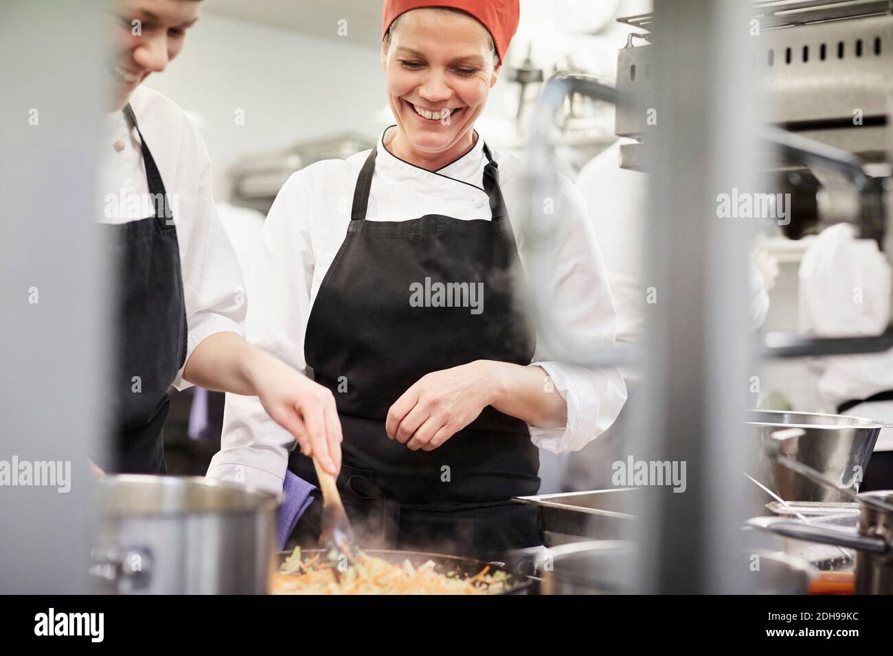 Lehrer beobachten weiblichen Koch Schüler Kochen Essen in der Küche bei Restaurant Stockfoto
