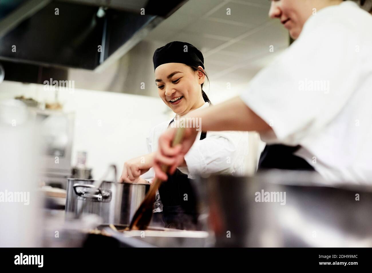 Lächelnde Chefstudentin mit Kollegen, die Essen im Werbespot kochen Küche Stockfoto