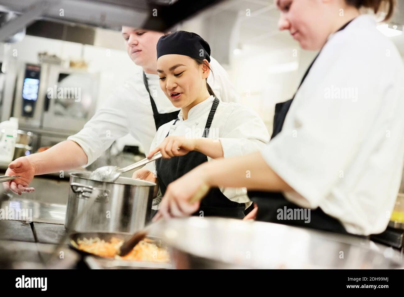 Männliche und weibliche Köche kochen Lebensmittel in der kommerziellen Küche Stockfoto