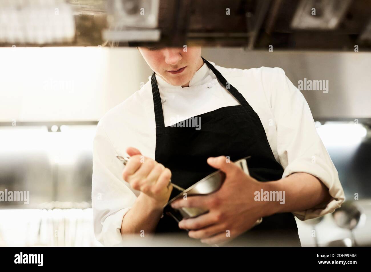 Mittelteil des männlichen Küchenchefs, der Lebensmittel in einer Schüssel in einem Werbespot mischt Küche Stockfoto