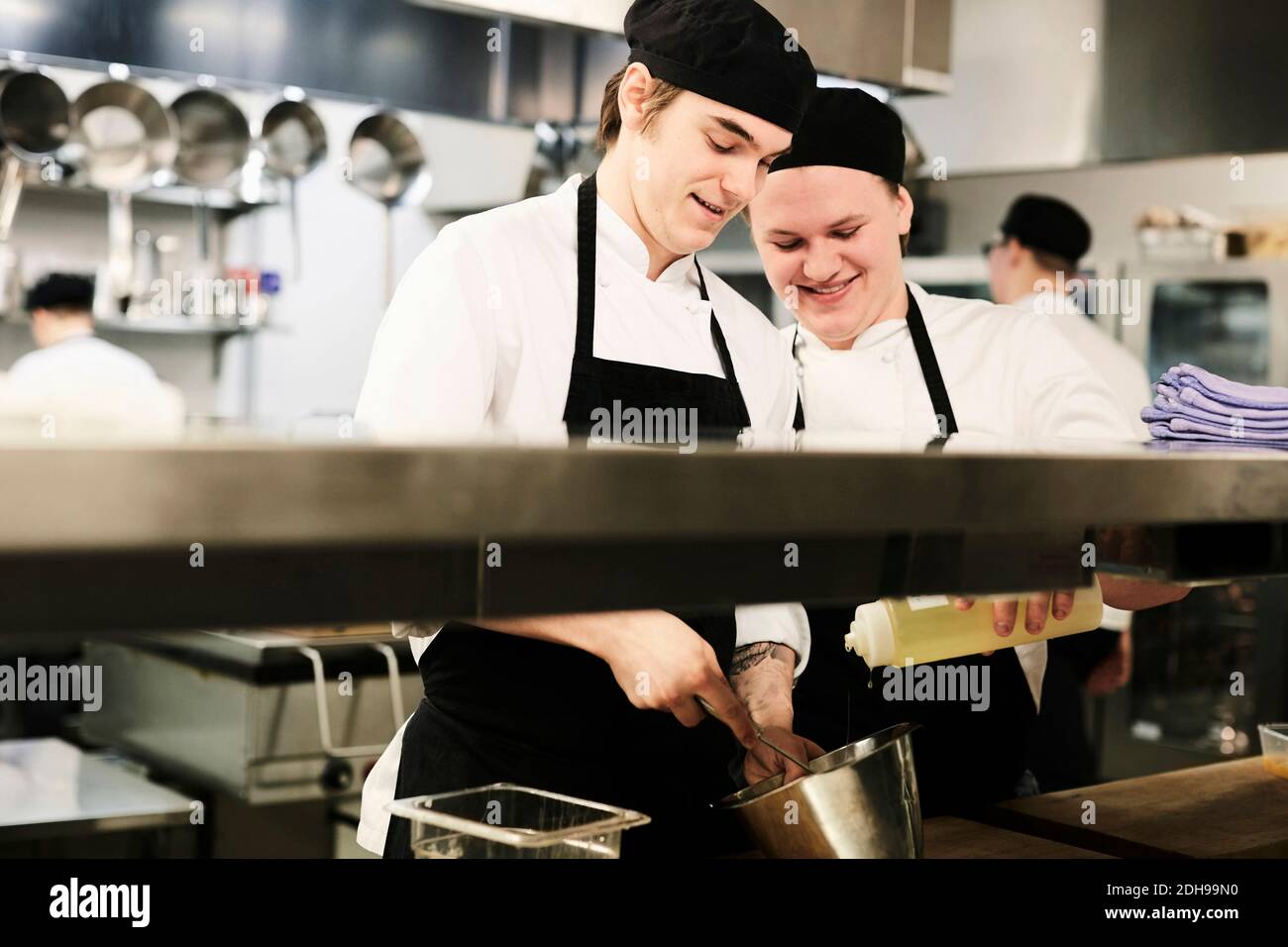 Junge männliche Köche kochen zusammen in der kommerziellen Küche Stockfoto