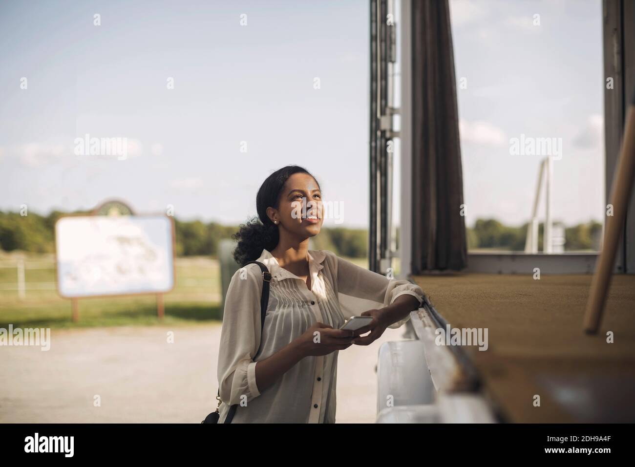 Junge Geschäftsfrau hält Mobiltelefon, während sie neben einem tragbaren Büro steht LKW Stockfoto