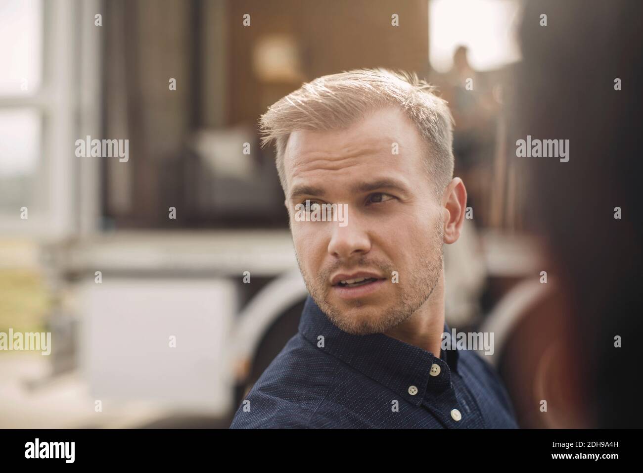 Junge Geschäftsmann schaut weg mit tragbaren Büro-LKW im Hintergrund Stockfoto