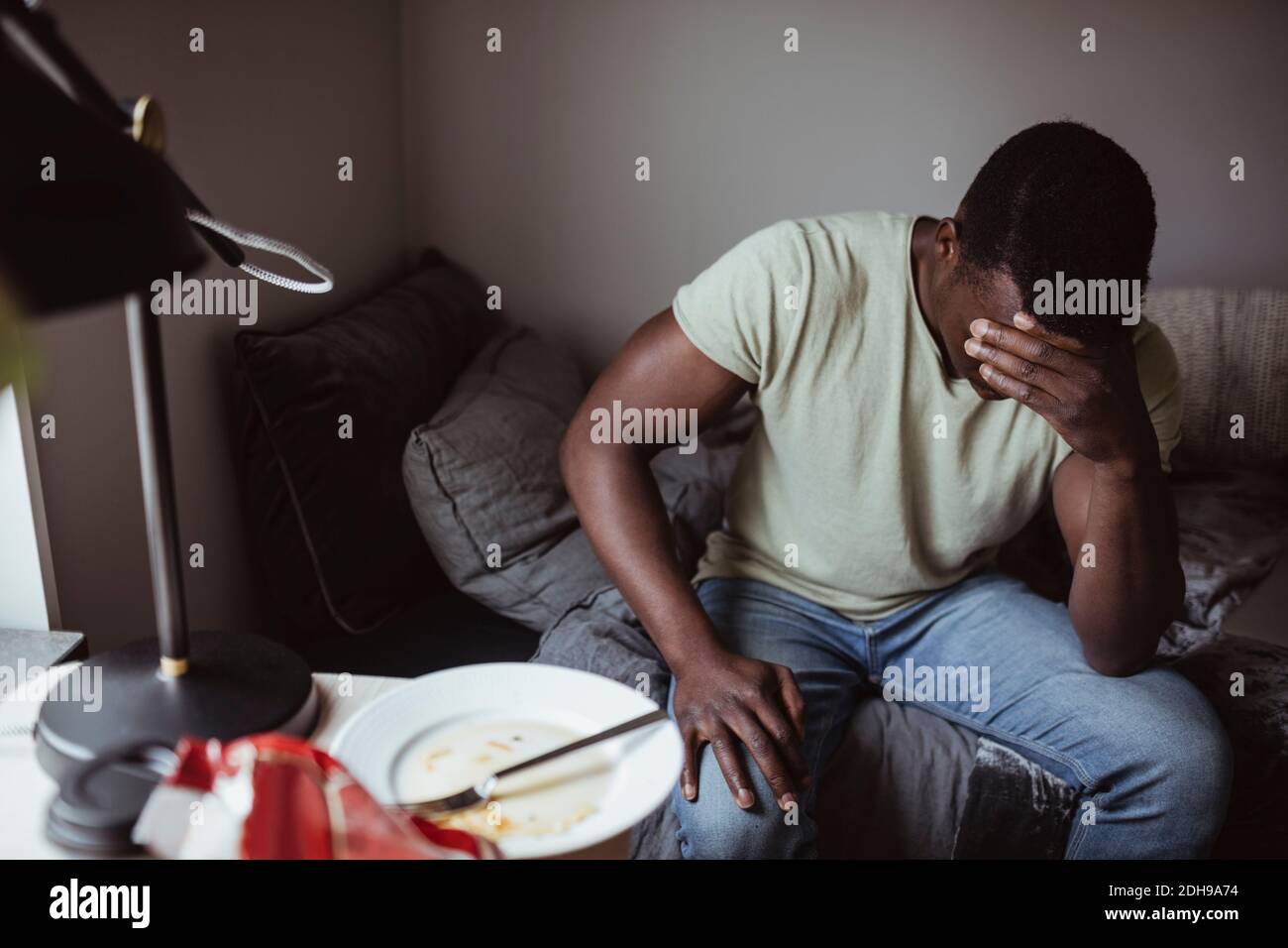 Besorgter Mann, der zu Hause auf dem Bett sitzt Stockfoto