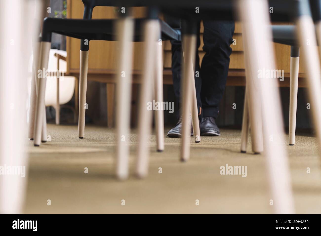 Niedriger Teil des Geschäftsmannes, der an Stühlen in einem tragbaren Büro steht LKW Stockfoto