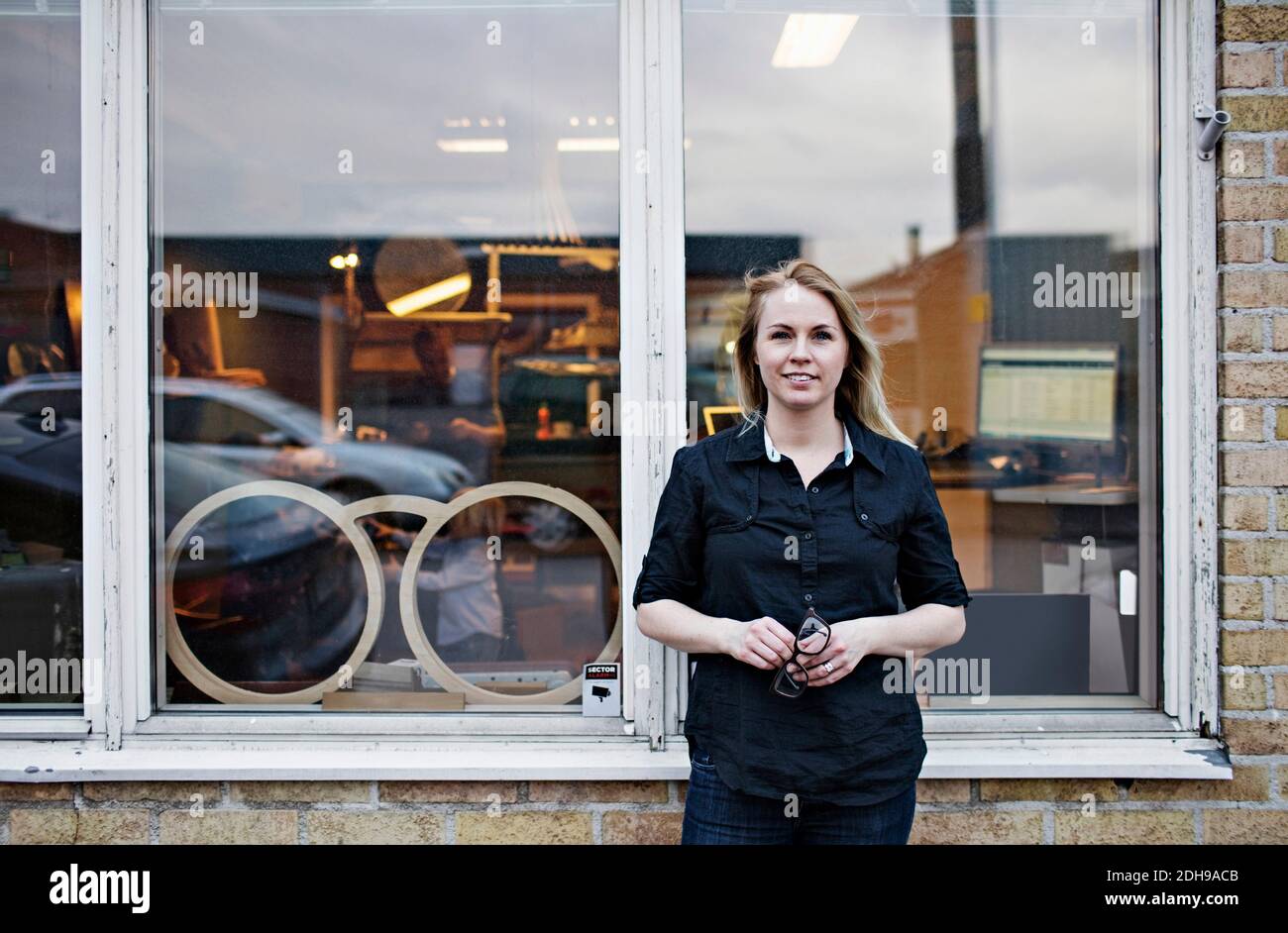 Portrait einer selbstbewussten Besitzerin, die vor der Brillen-Werkstatt steht Stockfoto