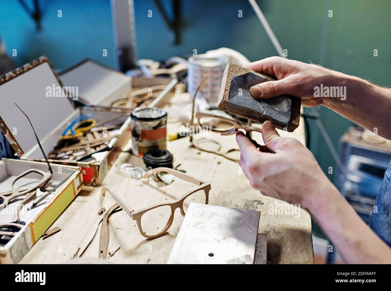 Zugeschnittenes Bild des männlichen Besitzers, der Brillen mit Arbeitswerkzeug reibt In der Werkstatt Stockfoto