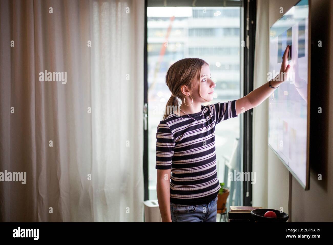Mädchen berühren digitale Anzeige des Fernsehgeräts im modernen Haus Stockfoto