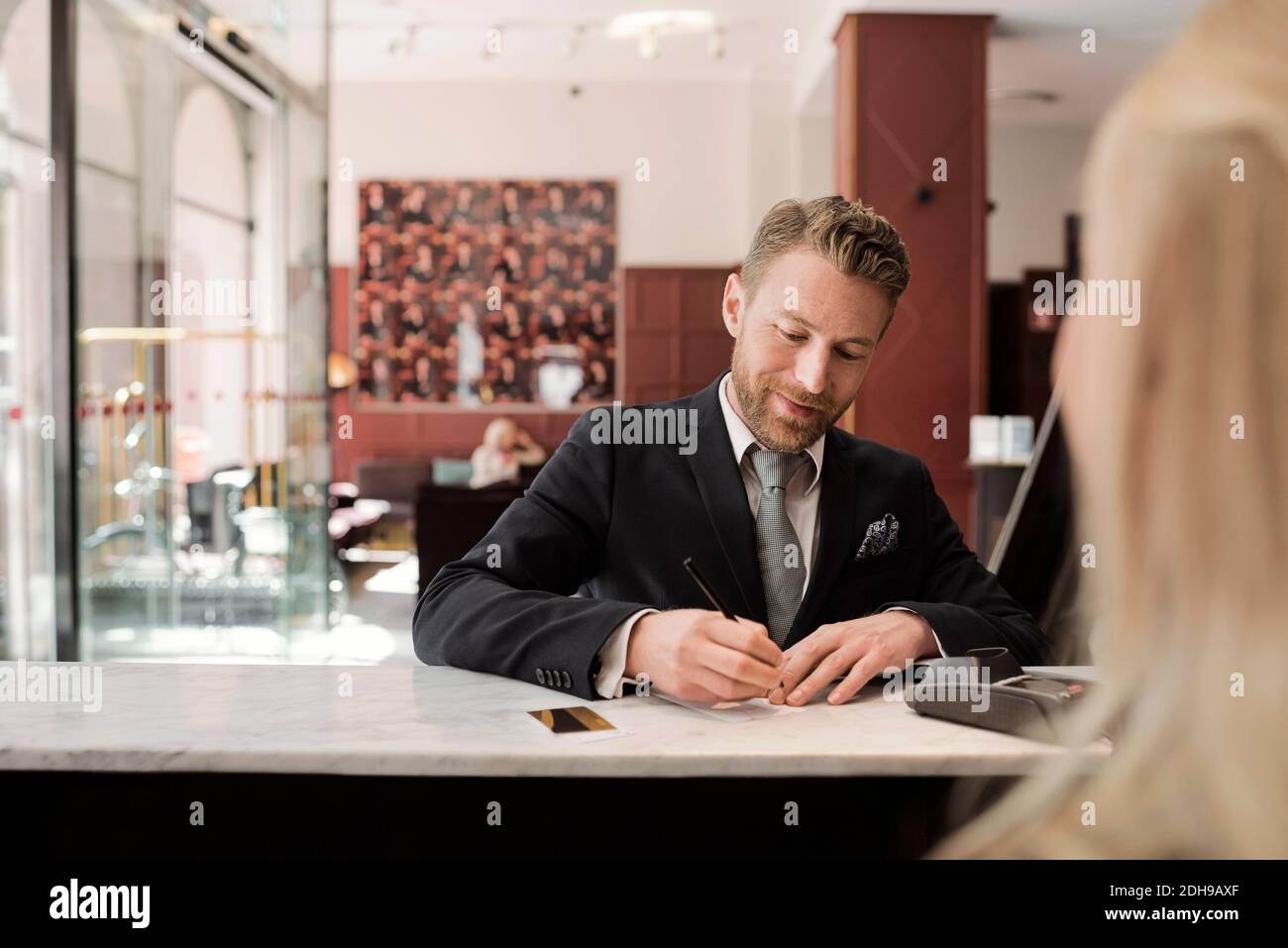 Ein reifer Geschäftsmann zahlt per Kreditkarte an der Hotelrezeption Stockfoto