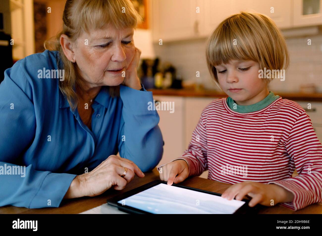 Ältere Frau, die Enkel mit einem digitalen Tablet betrachtet Stockfoto