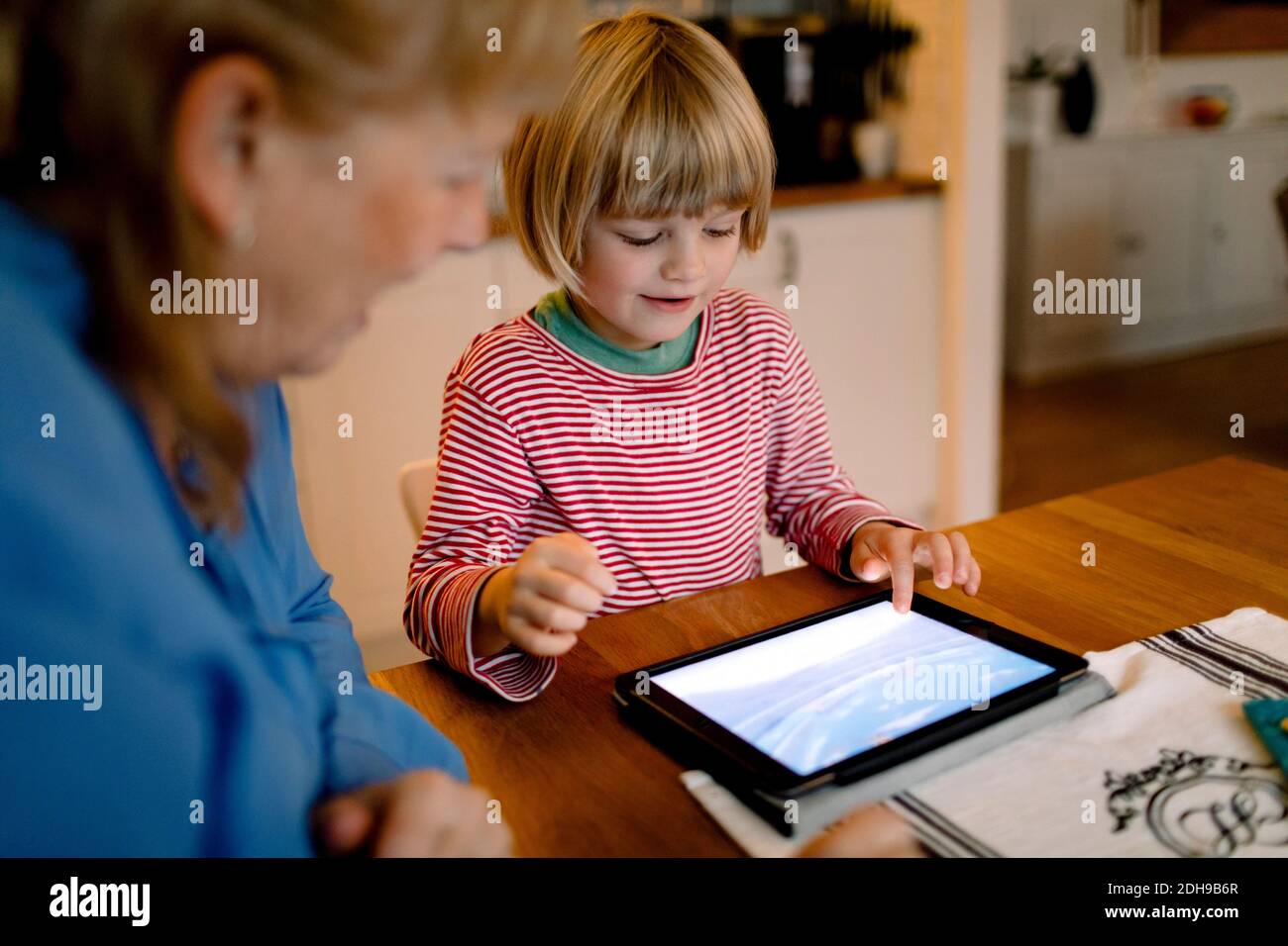 Großmutter betrachtet Enkel mit digitalen Tablet Stockfoto