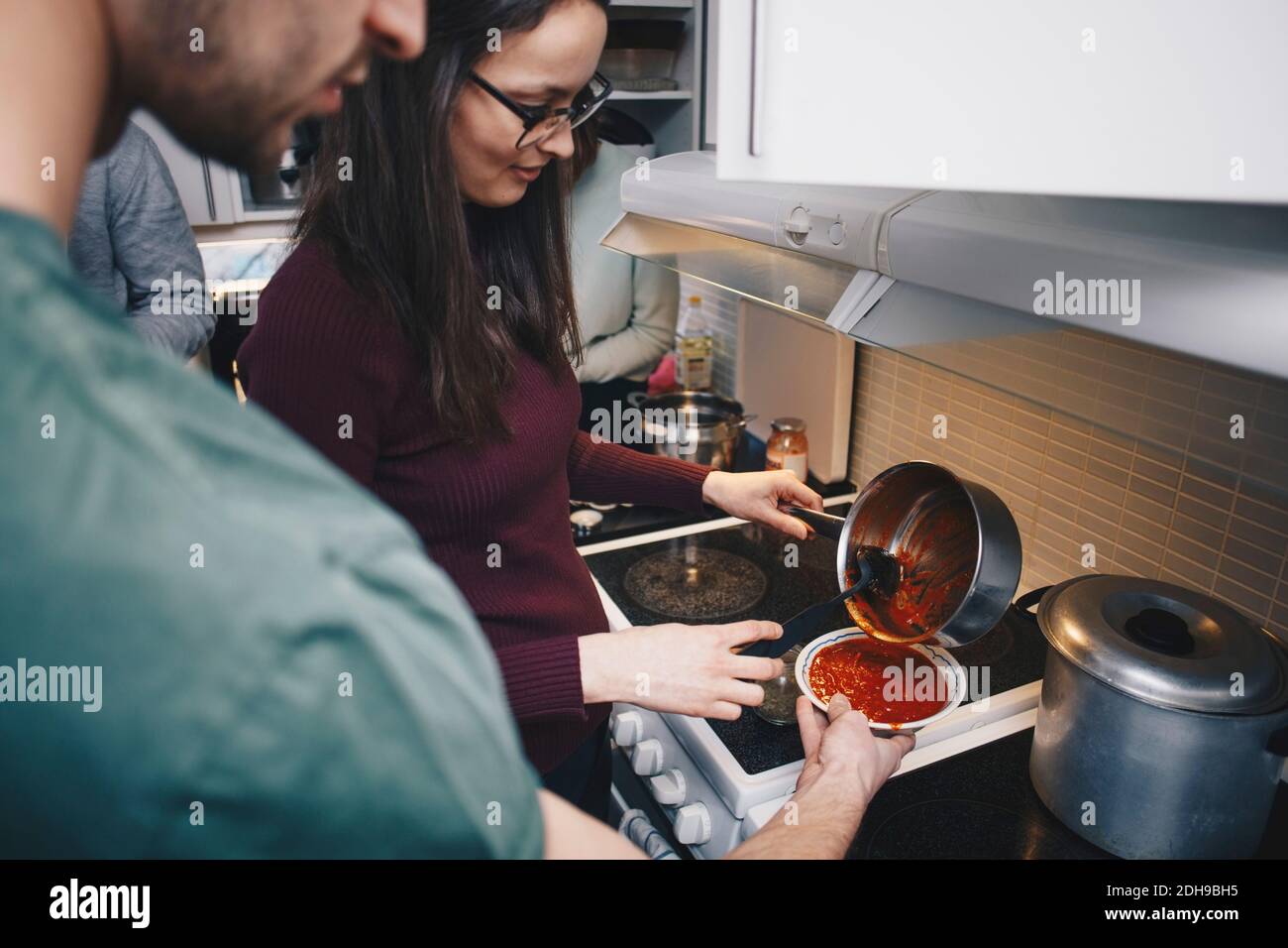 Aus der Sicht der Frau, die Tomatensuppe für den Mann gießt Halten Schüssel in der Küche Stockfoto