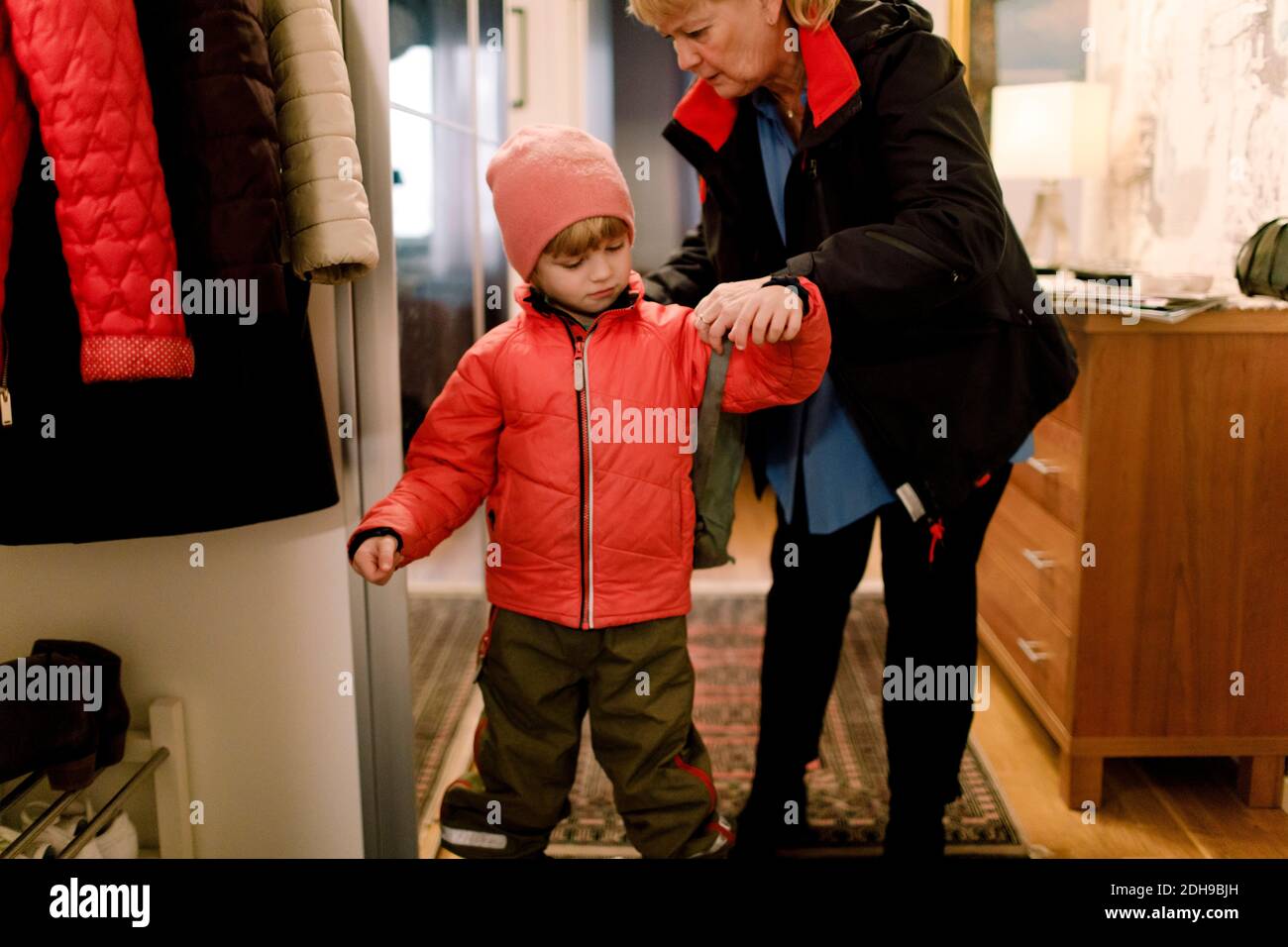 Ältere Frau hilft Enkel in Tasche zu Hause tragen Stockfoto