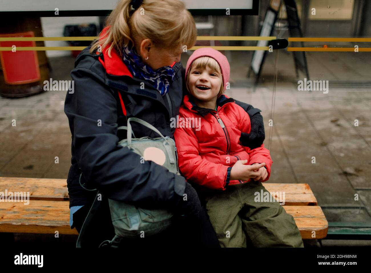 Großmutter mit lächelndem Enkel, der auf der Bank in der Stadt sitzt Stockfoto