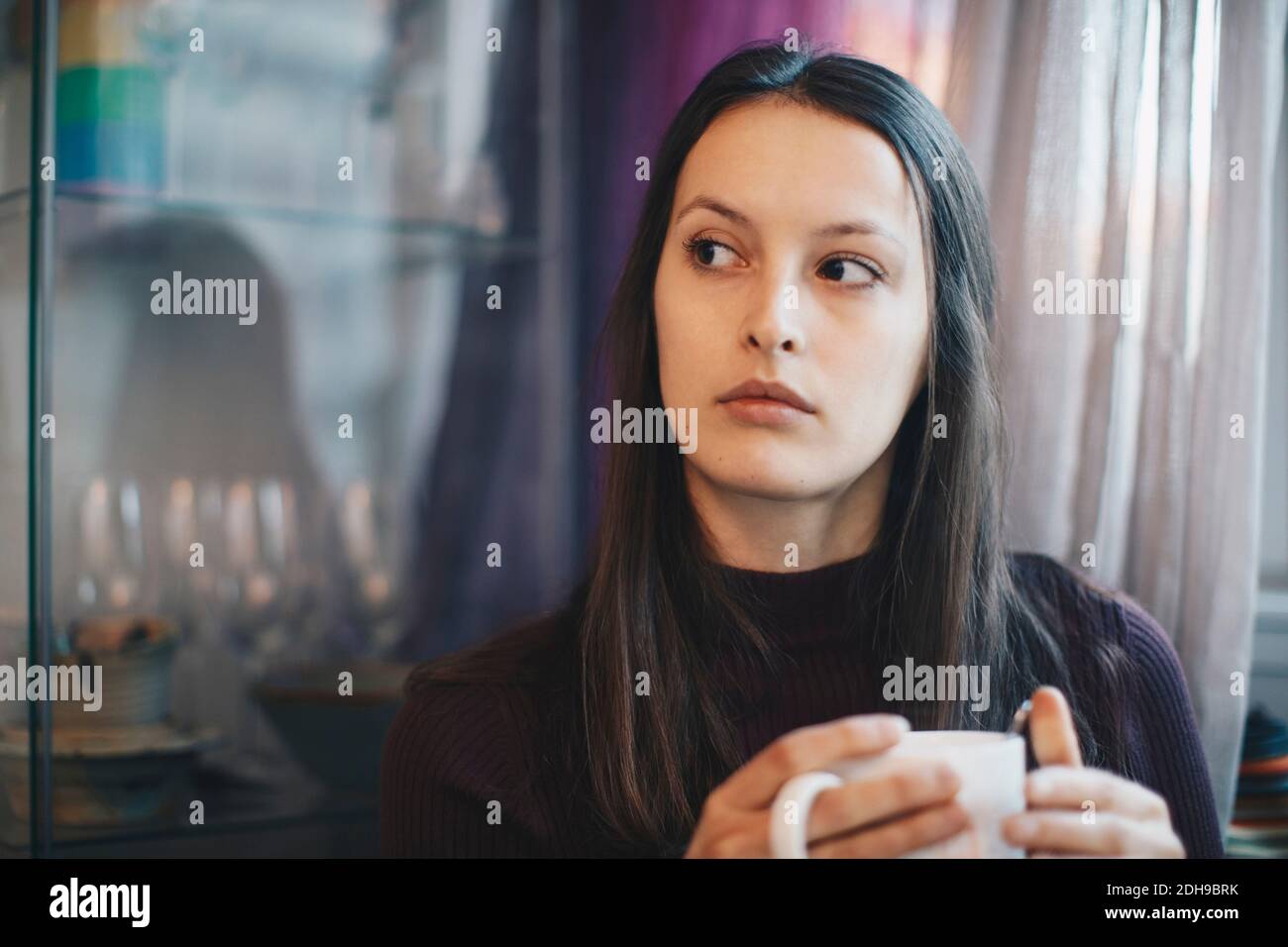 Junge Frau hält Kaffeetasse in Hochschule Wohnheim Zimmer Stockfoto