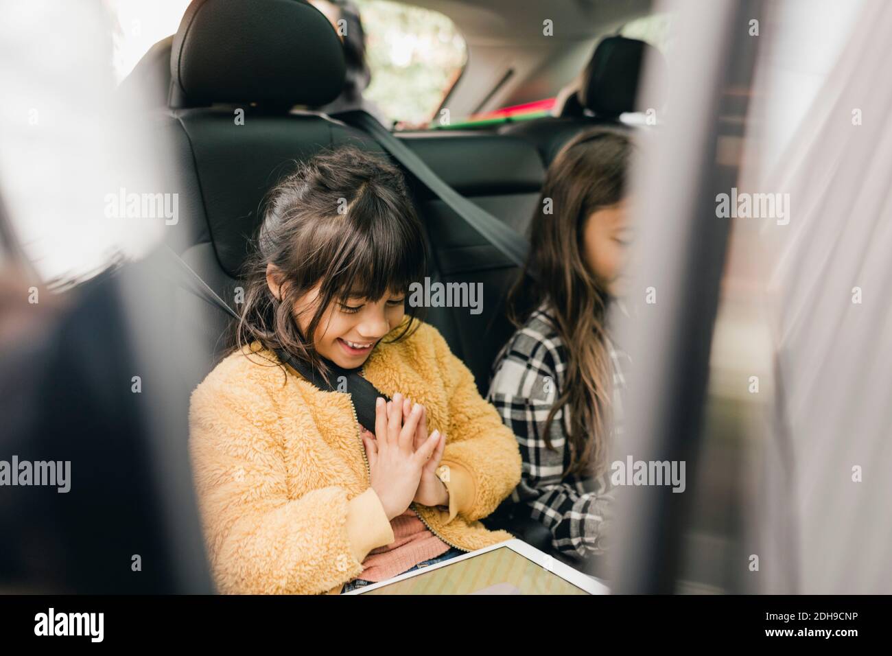 Lächelndes Mädchen mit digitalen Tablet, während im Auto sitzen Stockfoto