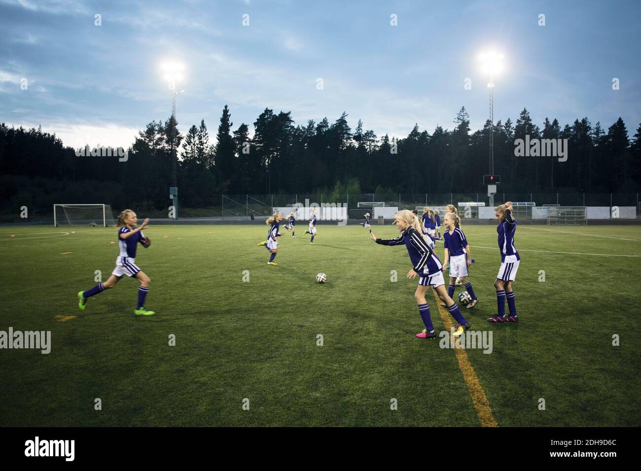 Mädchen laufen auf dem Fußballfeld gegen den Himmel Stockfoto