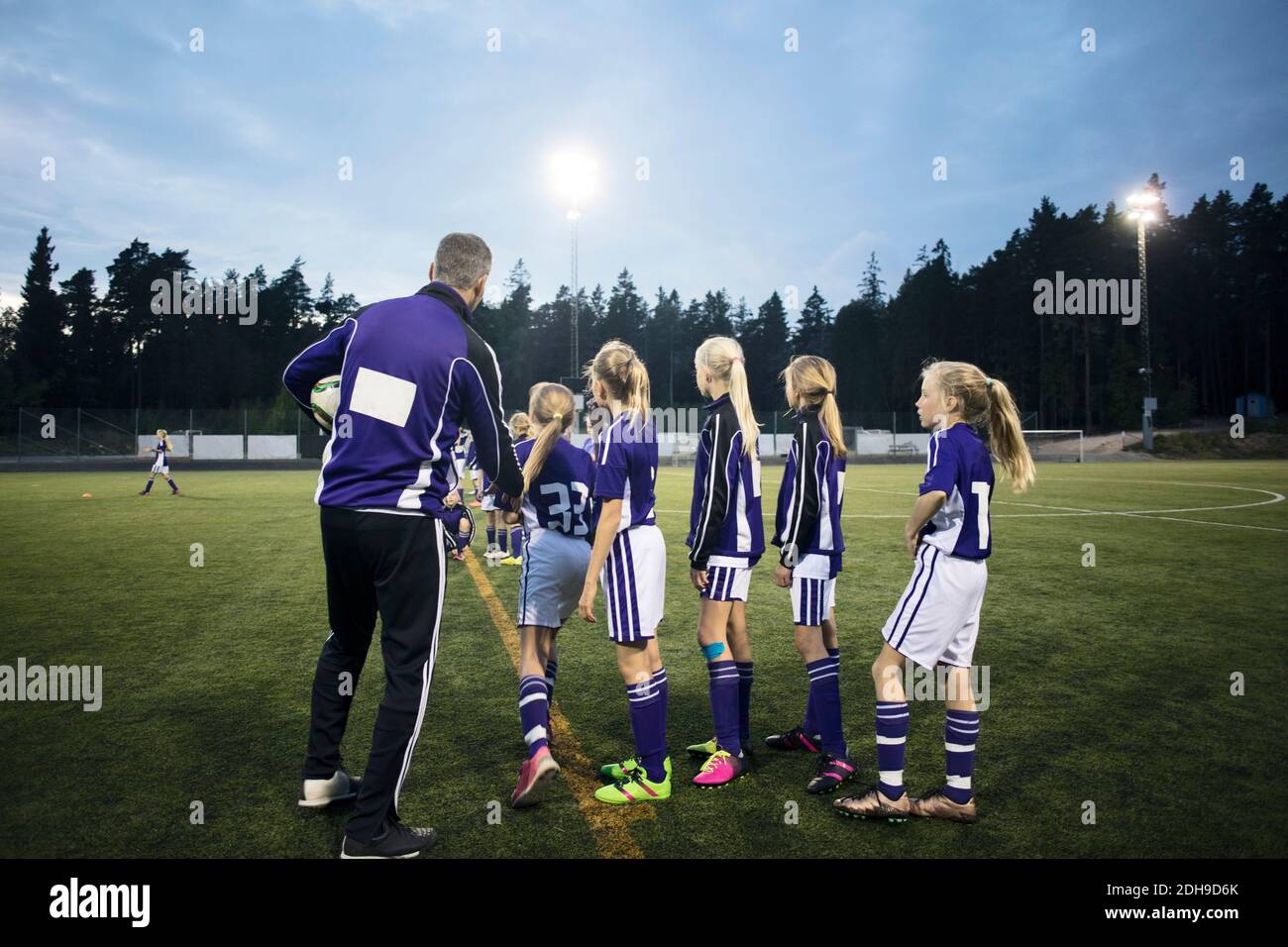 Trainer erklärt weibliche Fußballmannschaft auf dem Feld gegen Himmel Stockfoto
