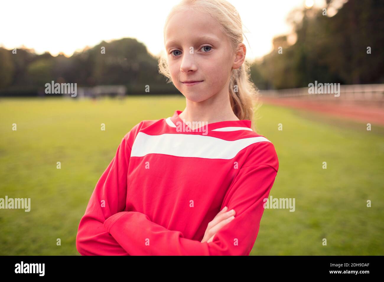 Portrait von selbstbewussten Mädchen stehen mit gekreuzten Armen bei Fußball Ein Stockfoto