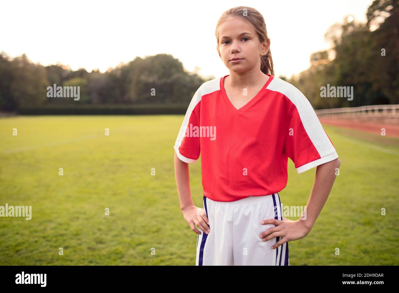 Porträt einer selbstbewussten Fußballspielerin, die mit Händen steht Hüfte im Feld Stockfoto