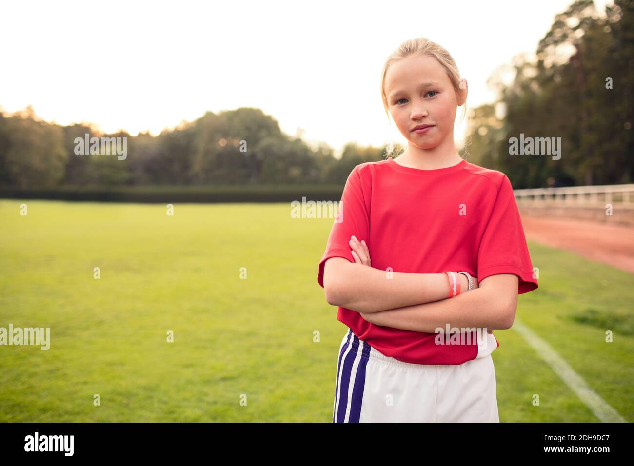 Porträt einer selbstbewussten Fußballspielerin, die mit gekreuzten Armen steht Auf dem Feld Stockfoto