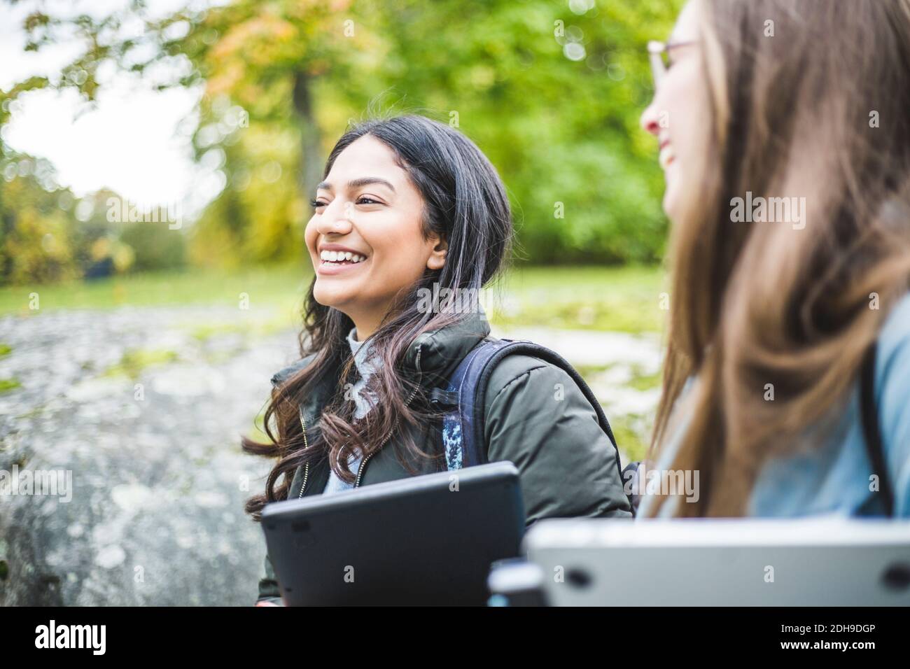 Lächelnde junge Frau mit Freundin auf dem Universitätscampus Stockfoto