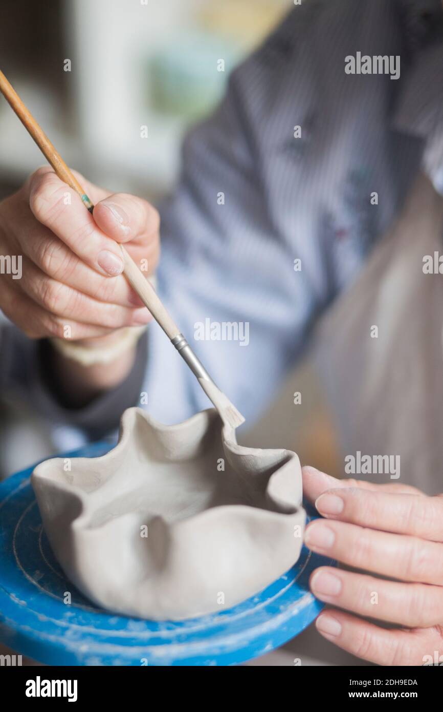 Mittelteil der älteren weiblichen Töpfer mit Pinsel auf Vase bei Werkstatt Stockfoto