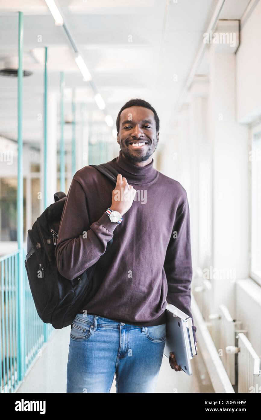 Porträt eines lächelnden männlichen Studenten im Korridor der Universität Stockfoto